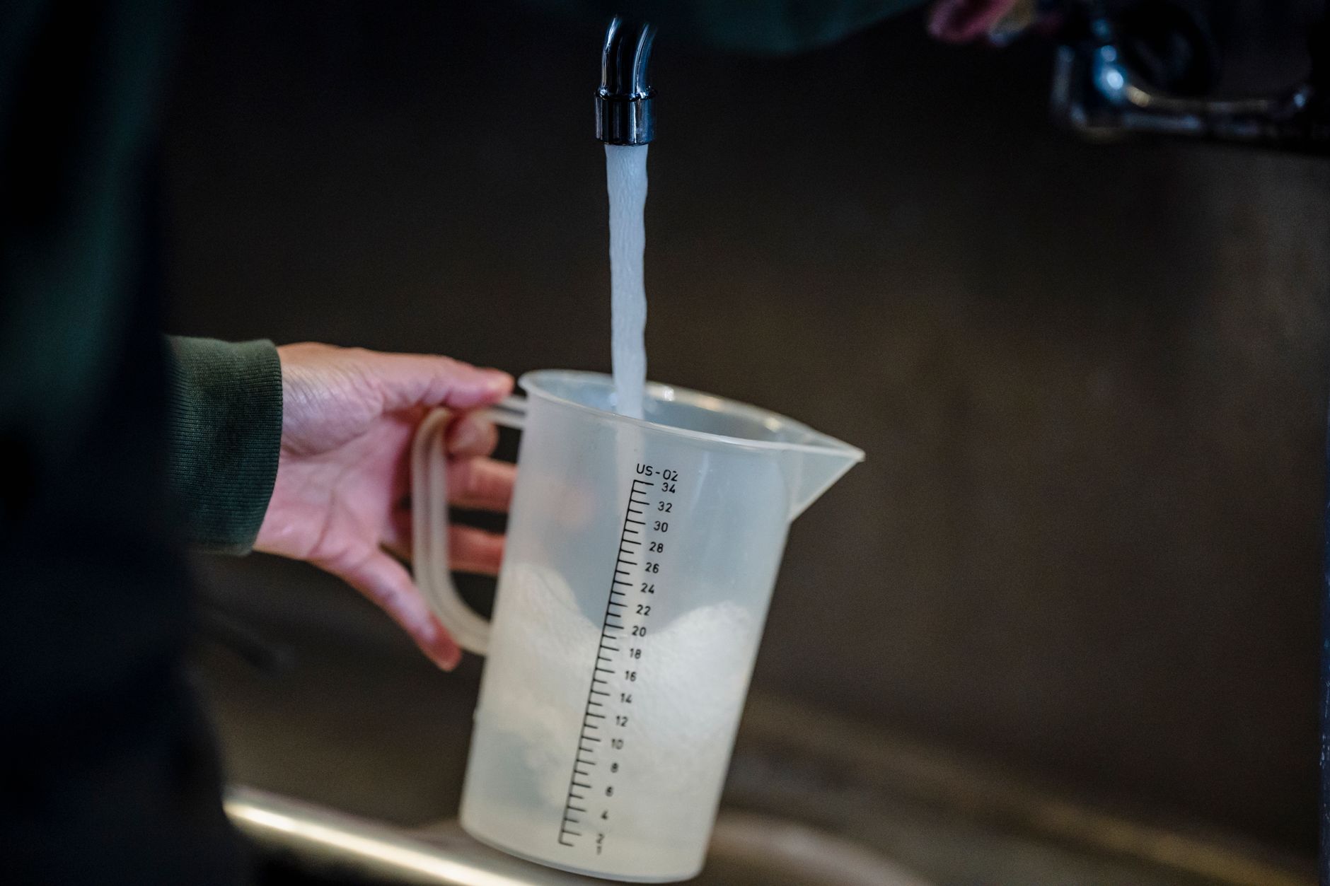 a person filling clean water jugs from a kitchen tap during a power outage